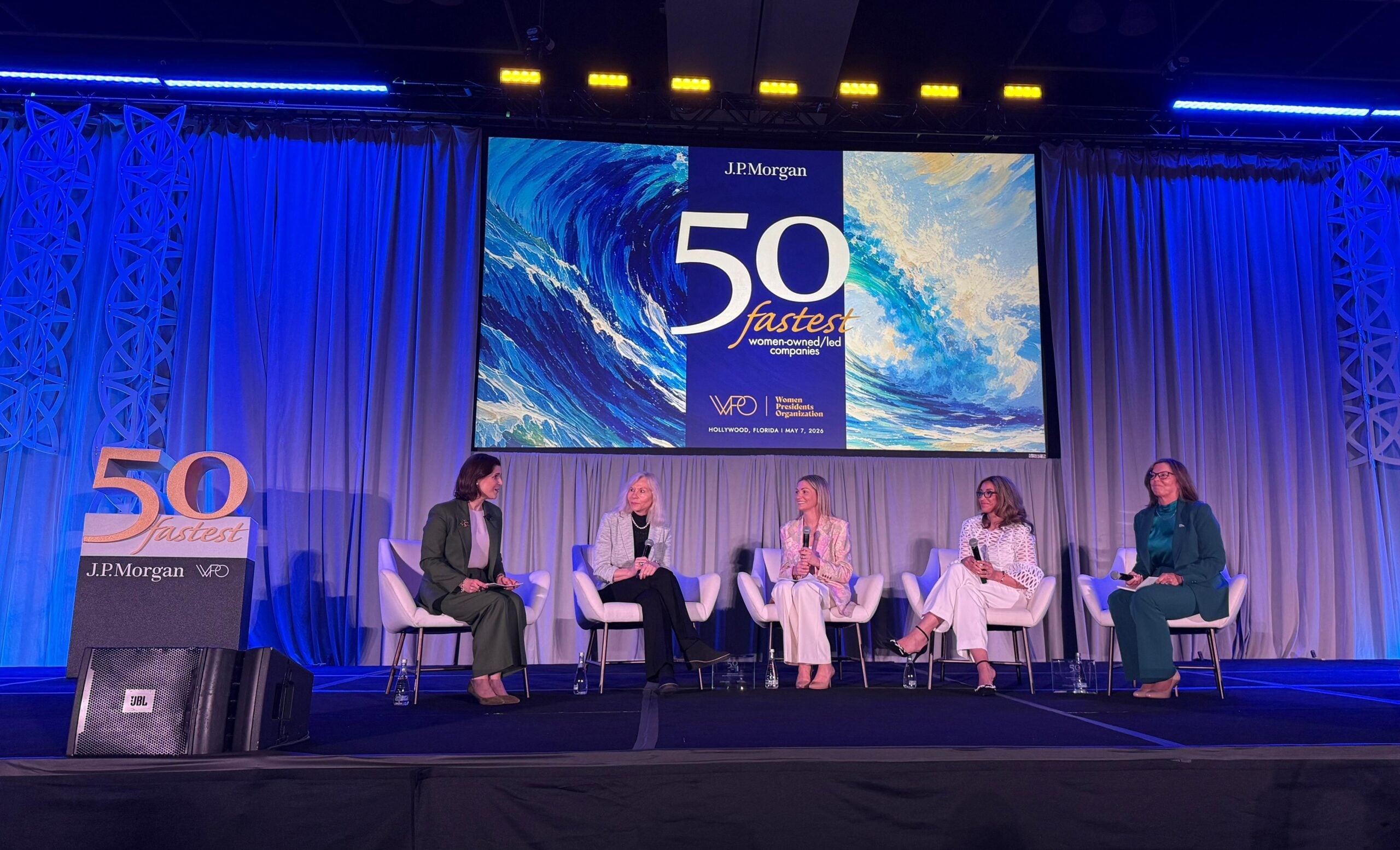 Panel discussion at the 50 Fastest event with five women speakers on stage.